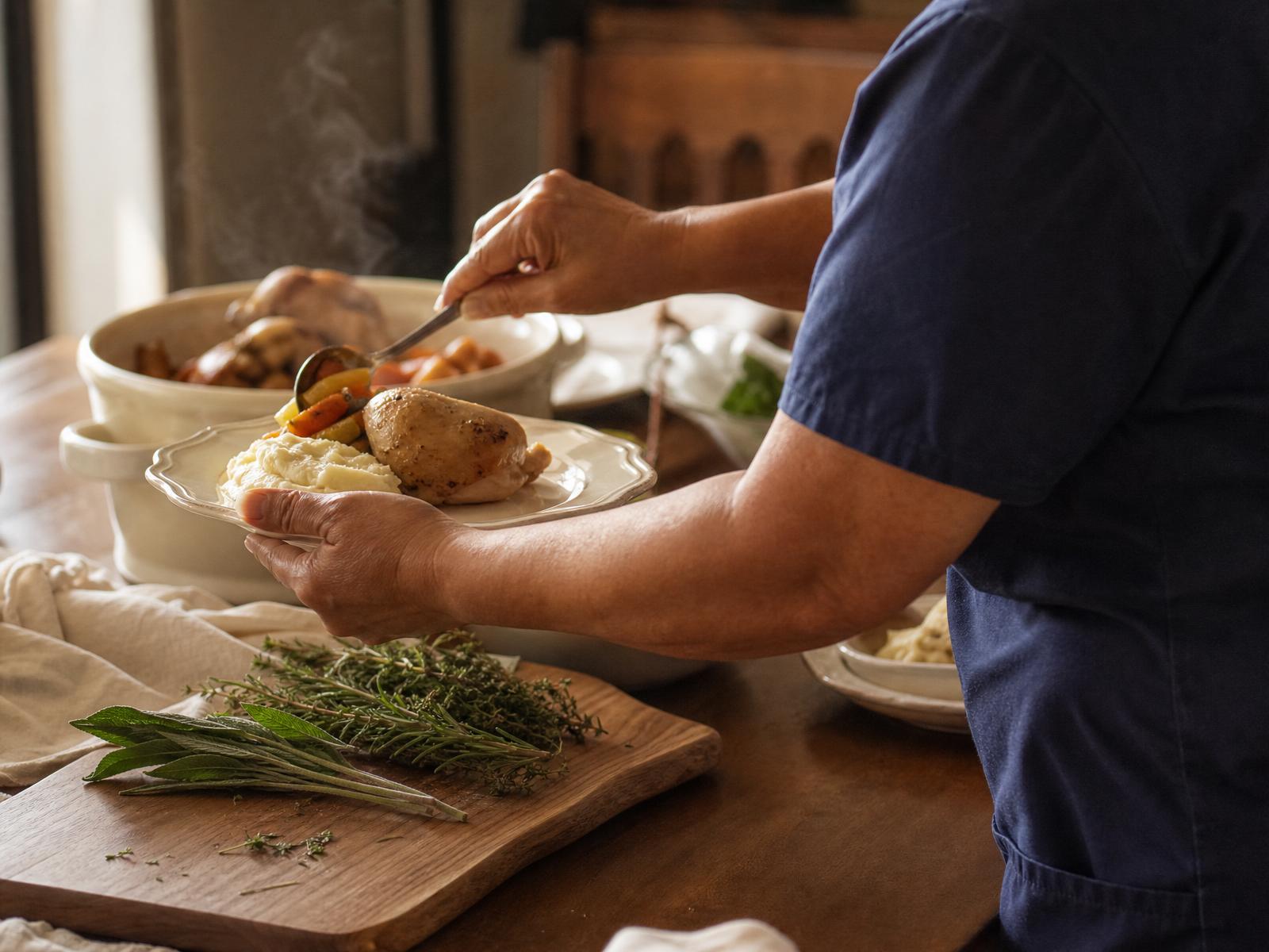 A caregiver plating a home-cooked meal of roasted chicken and vegetables